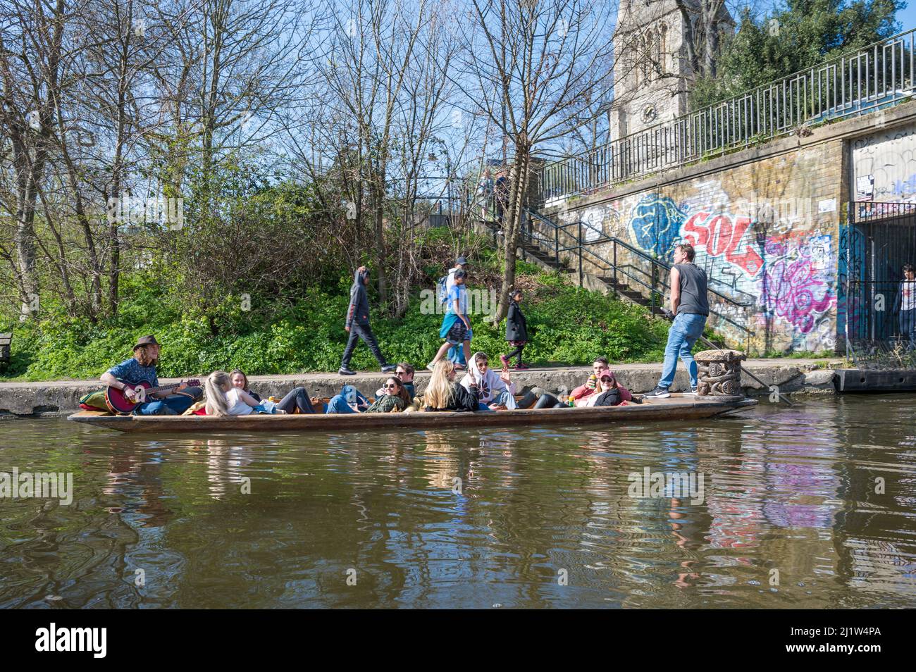 People enjoy a boat ride along the Regents Canal on a traditional punt boat with a live musical performance on board. London, England, UK. Stock Photo