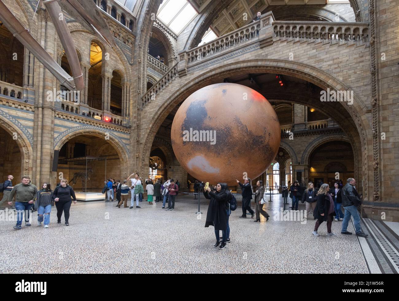 Luke Jerram Mars; people looking at the 7 metre Art Model of Mars by Luke Jerram in the main hall of the Natural History Museum, London UK Stock Photo