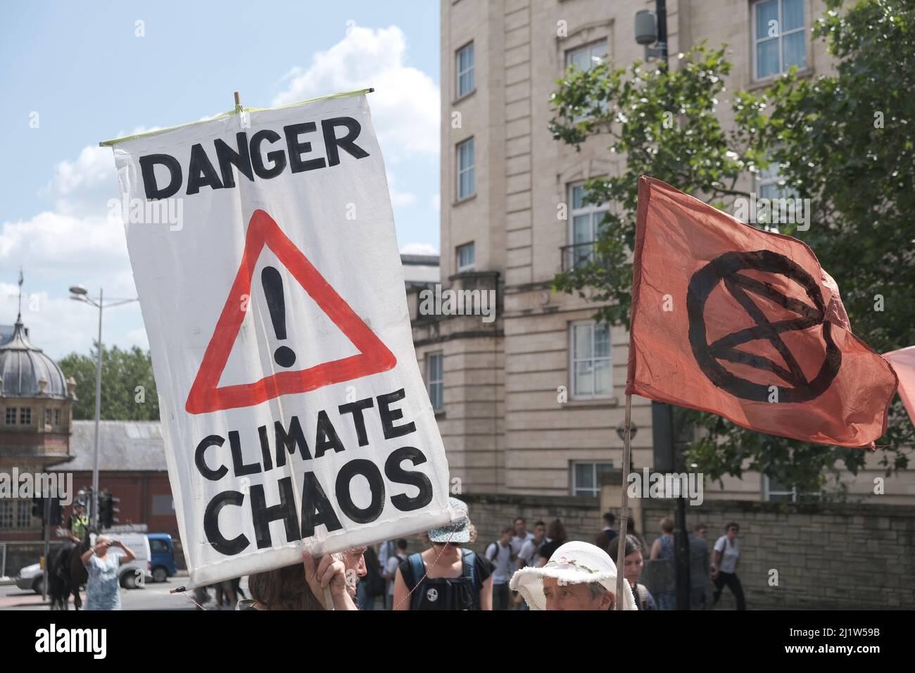 'Danger climate chaos' placard and Extinction Rebellion flag. Climate change protest march, Bristol, England, UK. 16 July 2019. Stock Photo