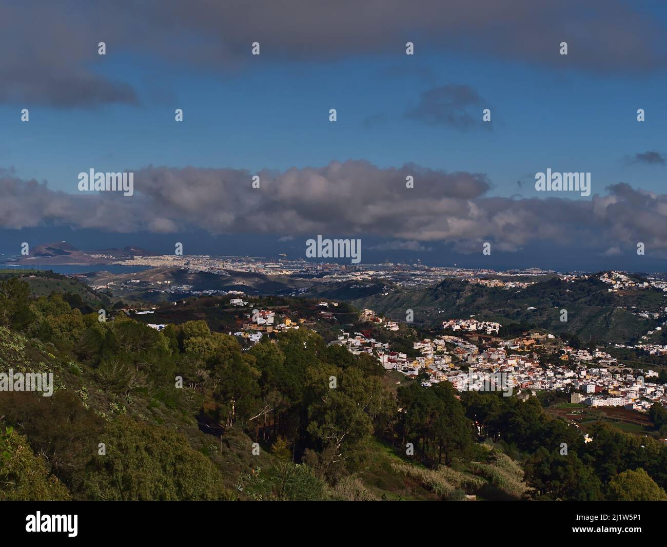 View over the northeast of island Gran Canaria, Spain with small village Teror surrounded by green hills and capital city Las Palmas in background. Stock Photo