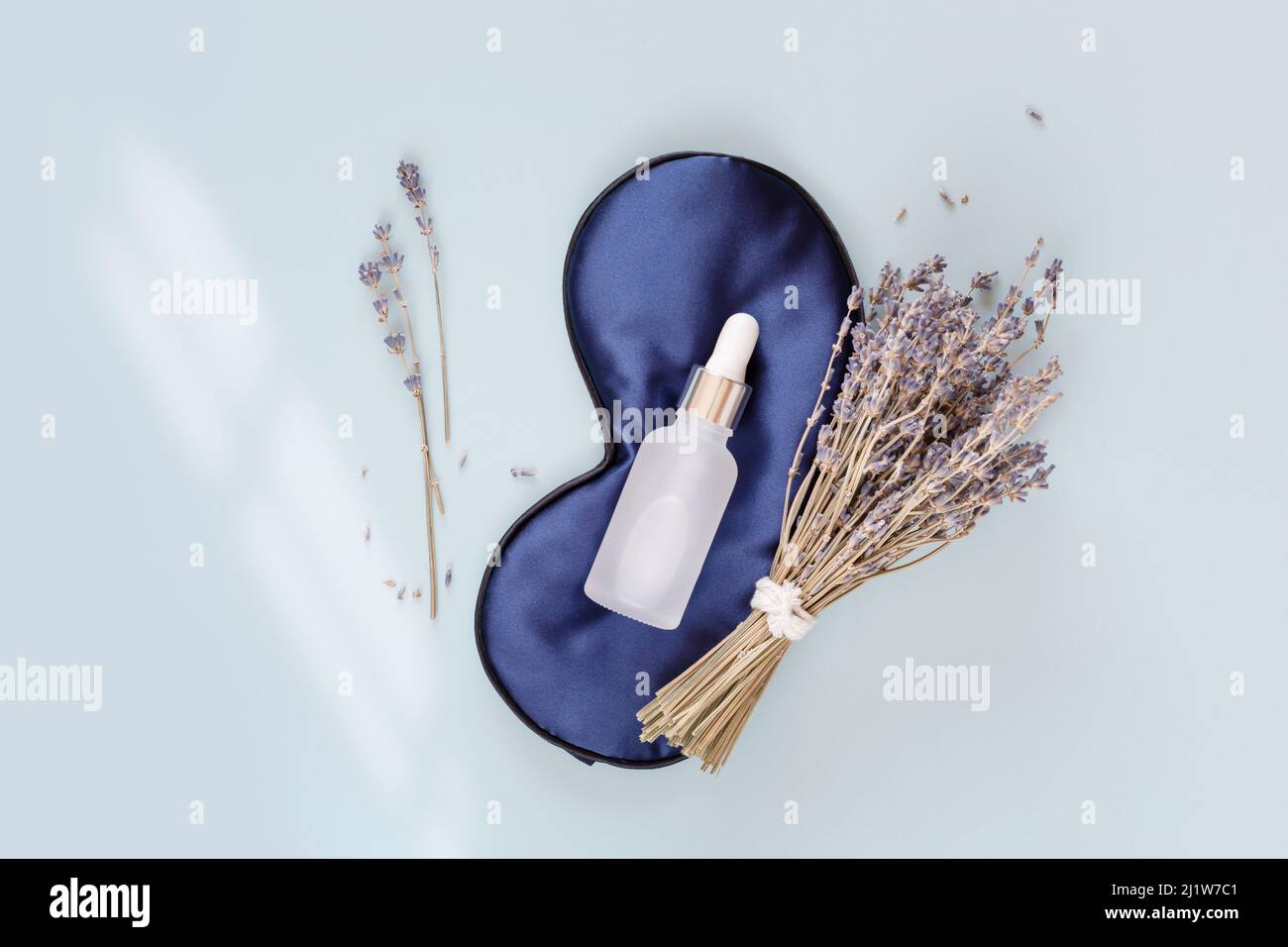 Relax composition with sleep mask, lavender oil and serum with lavender flowers on blue background. Lavender oil is the best natural remedy for treatm Stock Photo