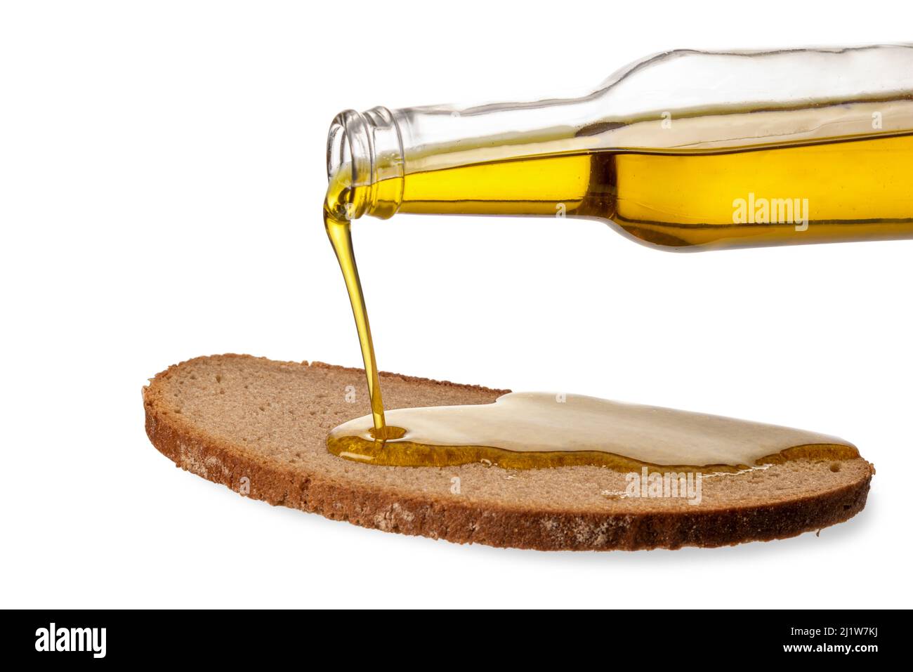Extra virgin olive oil pouring from glass bottle onto slice of rye bread, isolated on white, clipping path Stock Photo