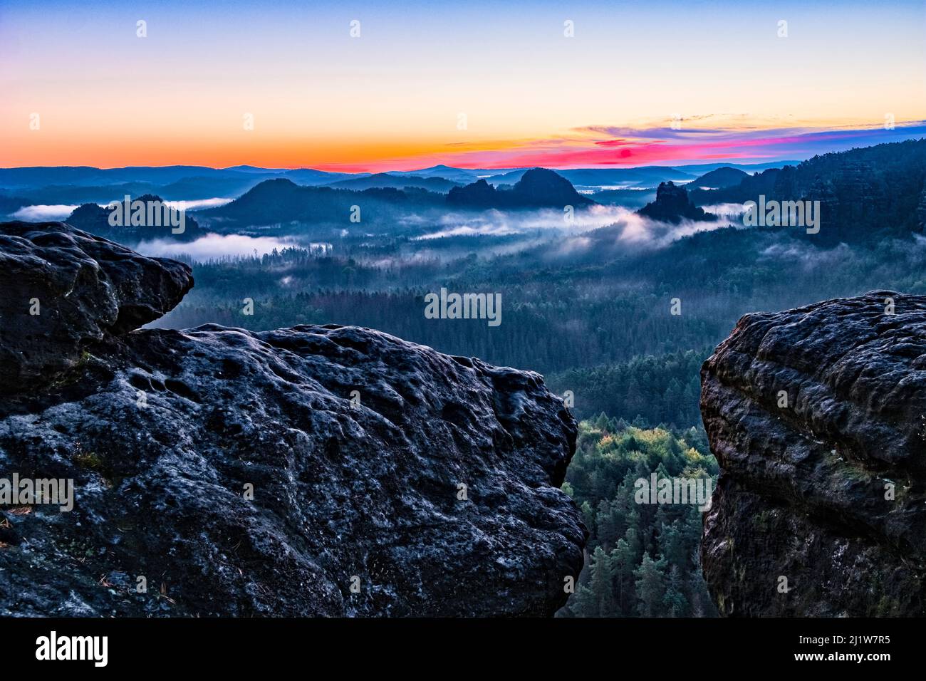 Landscape with rock formations in Zschand area of the Saxon Switzerland National Park covered in fog at sunrise. Stock Photo