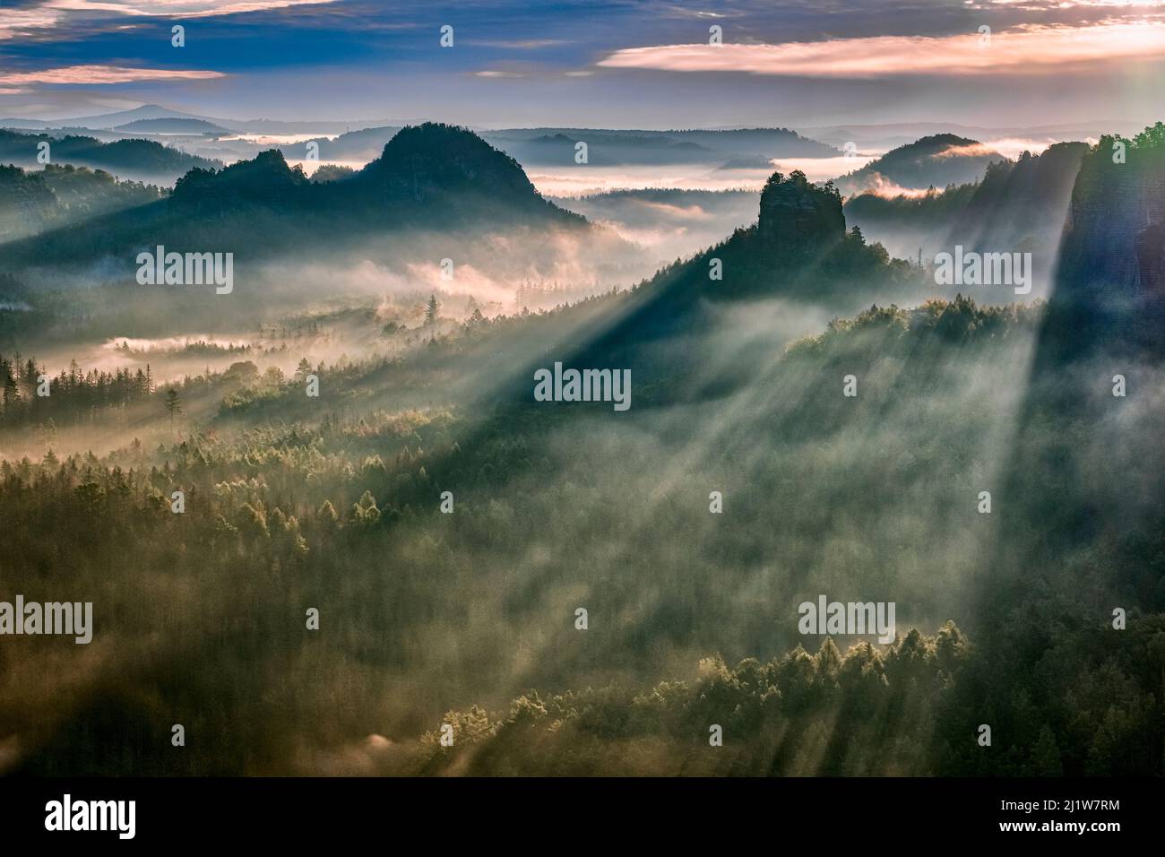 Landscape with rock formations and the summit Winterstein in Zschand area of the Saxon Switzerland National Park covered in fog at sunrise. Stock Photo