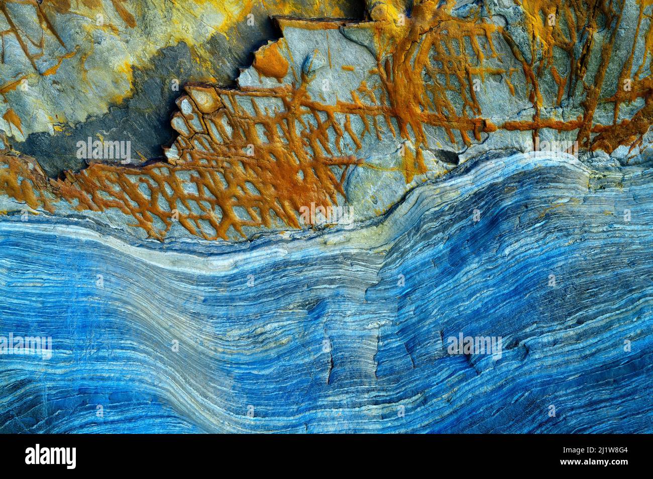 From below of massive rocky cliff with striped pattern in daytime as abstract background Stock Photo