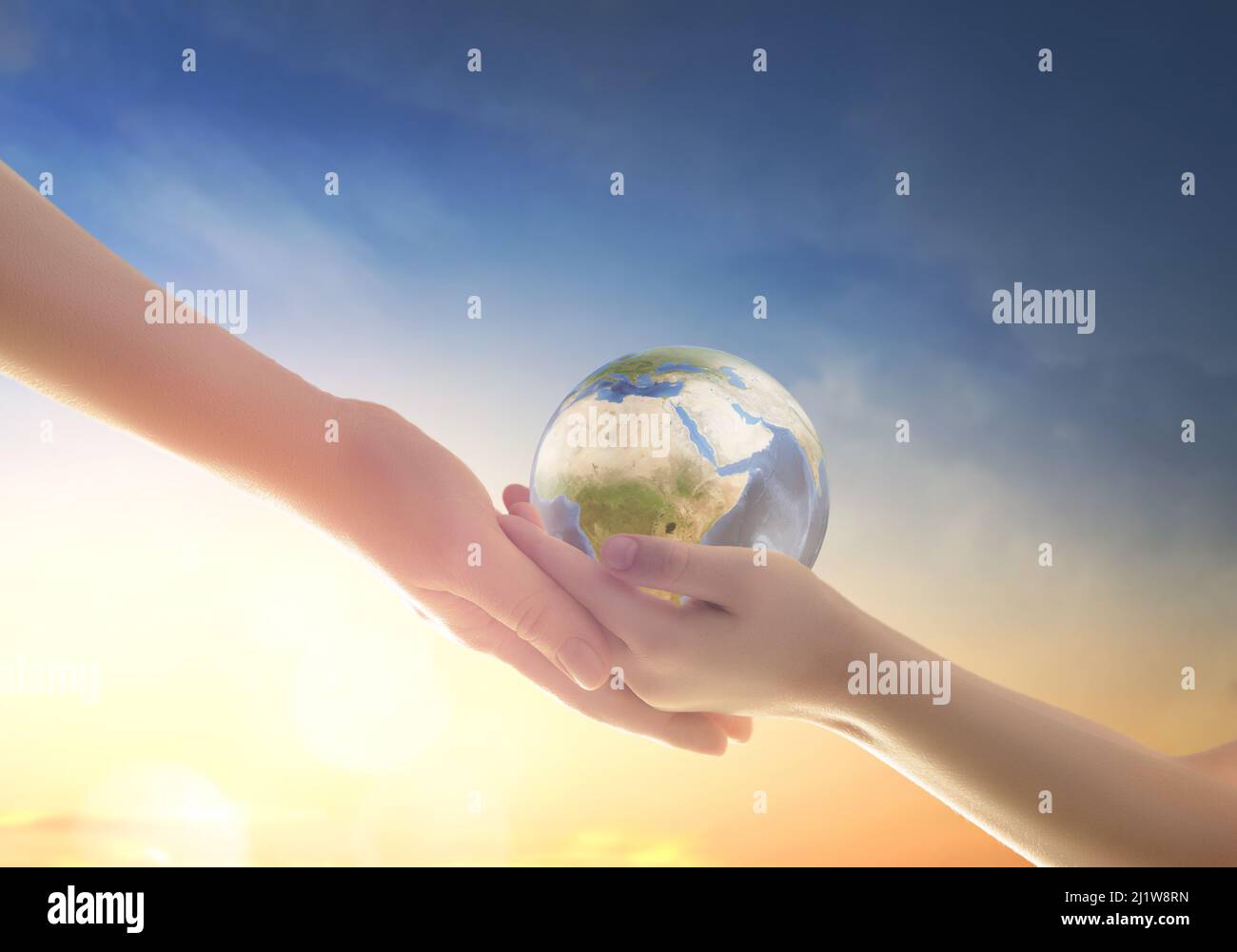 Child and adult holding planet in hands on sky background. Earth day ...