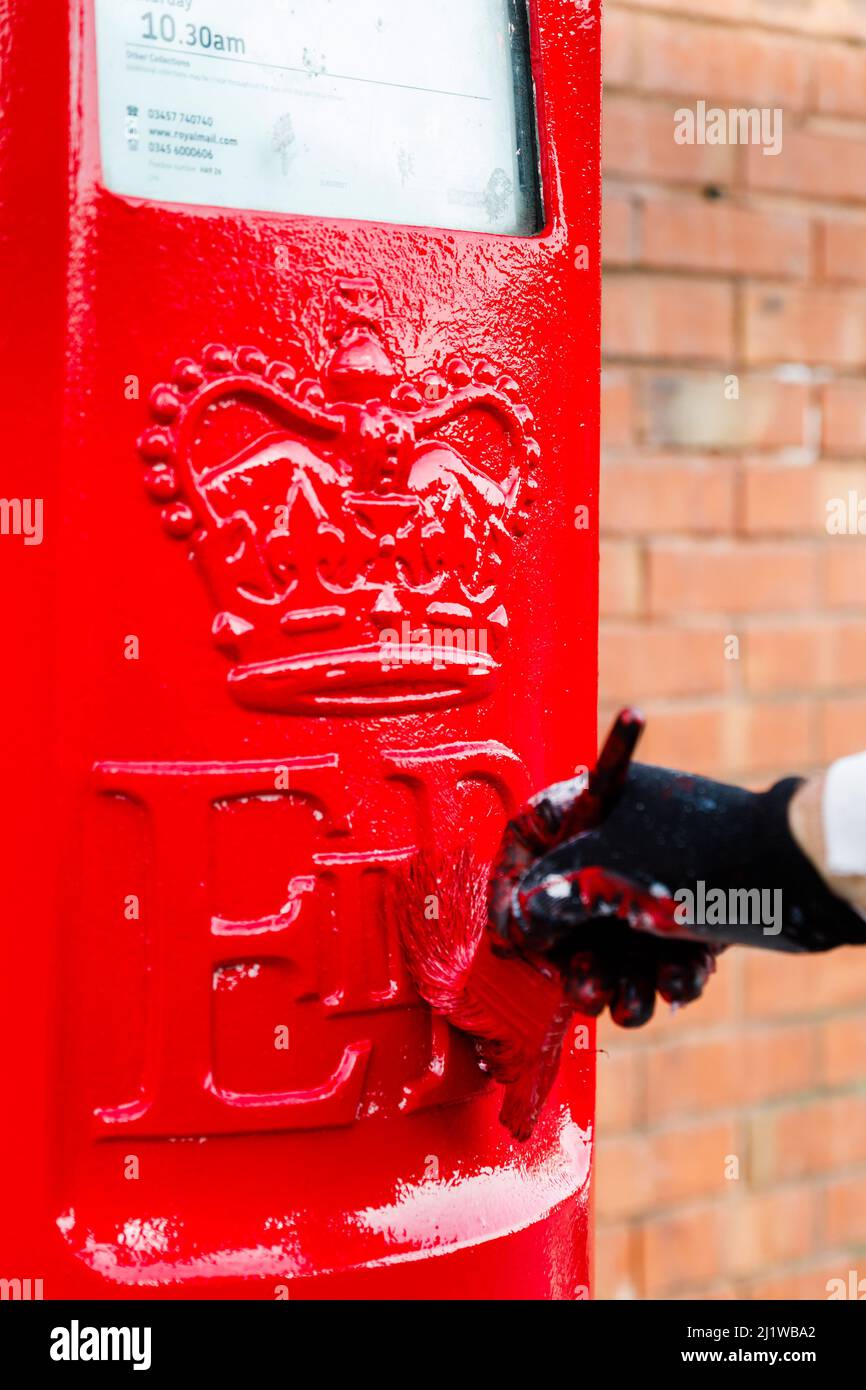 Wembley Park, UK. 28th March 2022.Royal Mails iconic red and black letterboxes get repaintd as part of their scheduled maintenance, approx. every 3 to 5 years. Having first applied a pink primer, within a few days, they are painted their traditional red and black colouring. Painter, Besim, has been repainting post boxes for 25 years. Amanda Rose/Alamy Live News Stock Photo