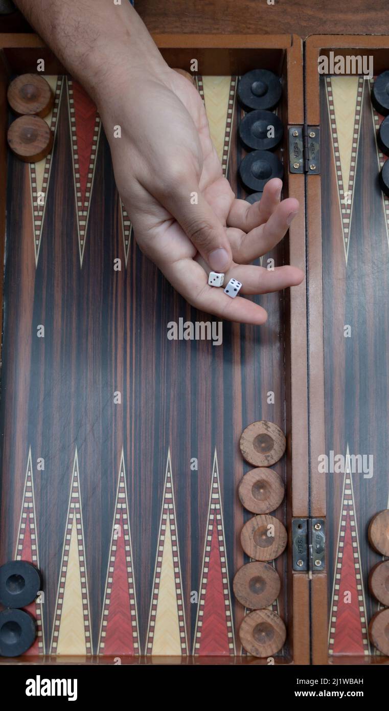 Close up woman hand holding backgammon dices and playing backgammon at outside. The focus is on her hand. Stock Photo