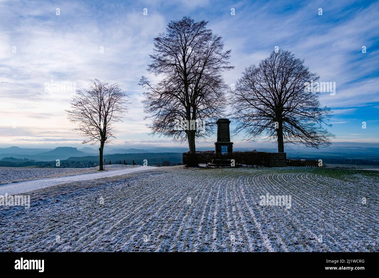 The tree formation Hohenburkersdorfer Linde and a Napoleon monument in the National Park Saxon Switzerland after snowfall in autumn. Stock Photo