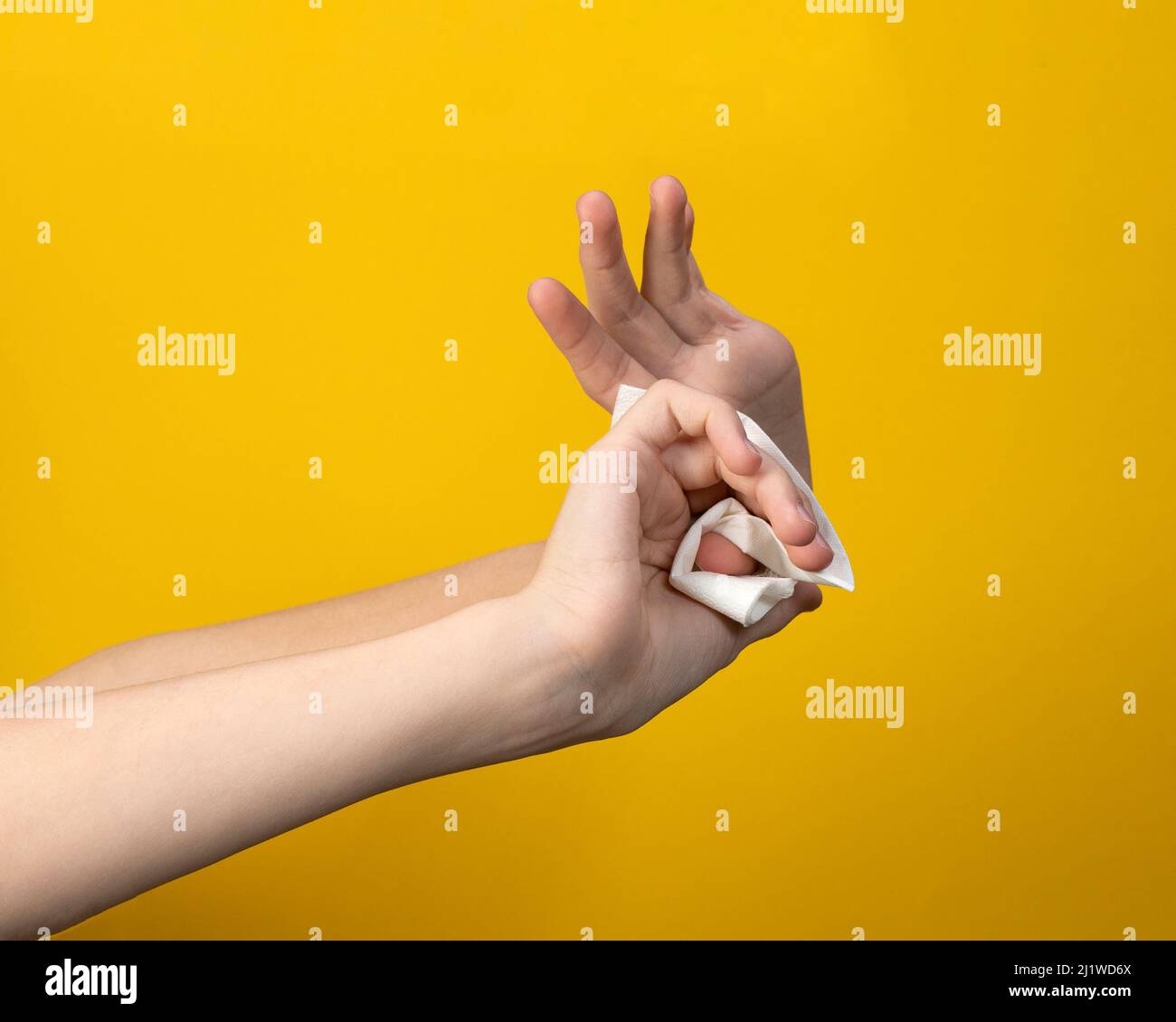 woman wipes her hands antimicrobial disinfection napkin on yellow background Stock Photo