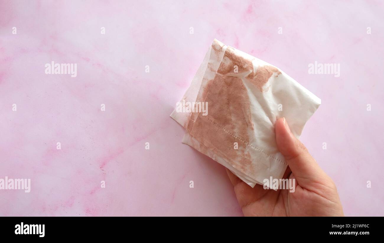 Hand holding a piece of tissue paper with stain from wiping off makeup powder. Stock Photo