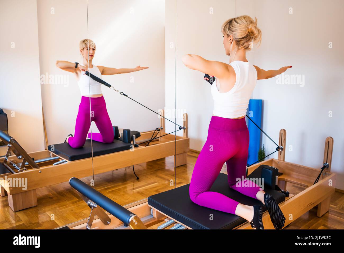 Woman doing pilates arm work with resistance straps on a reformer bed to  strengthen and tone her muscles in a health and fitness concept Stock Photo  - Alamy