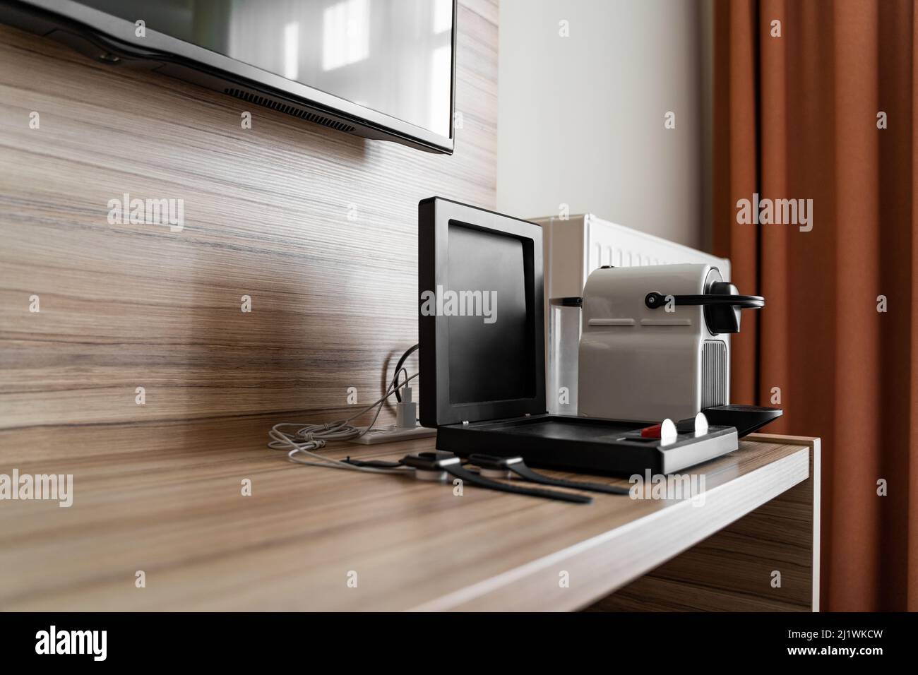 Two black apple watch on charge, coffee machine with capsules on wooden table Stock Photo