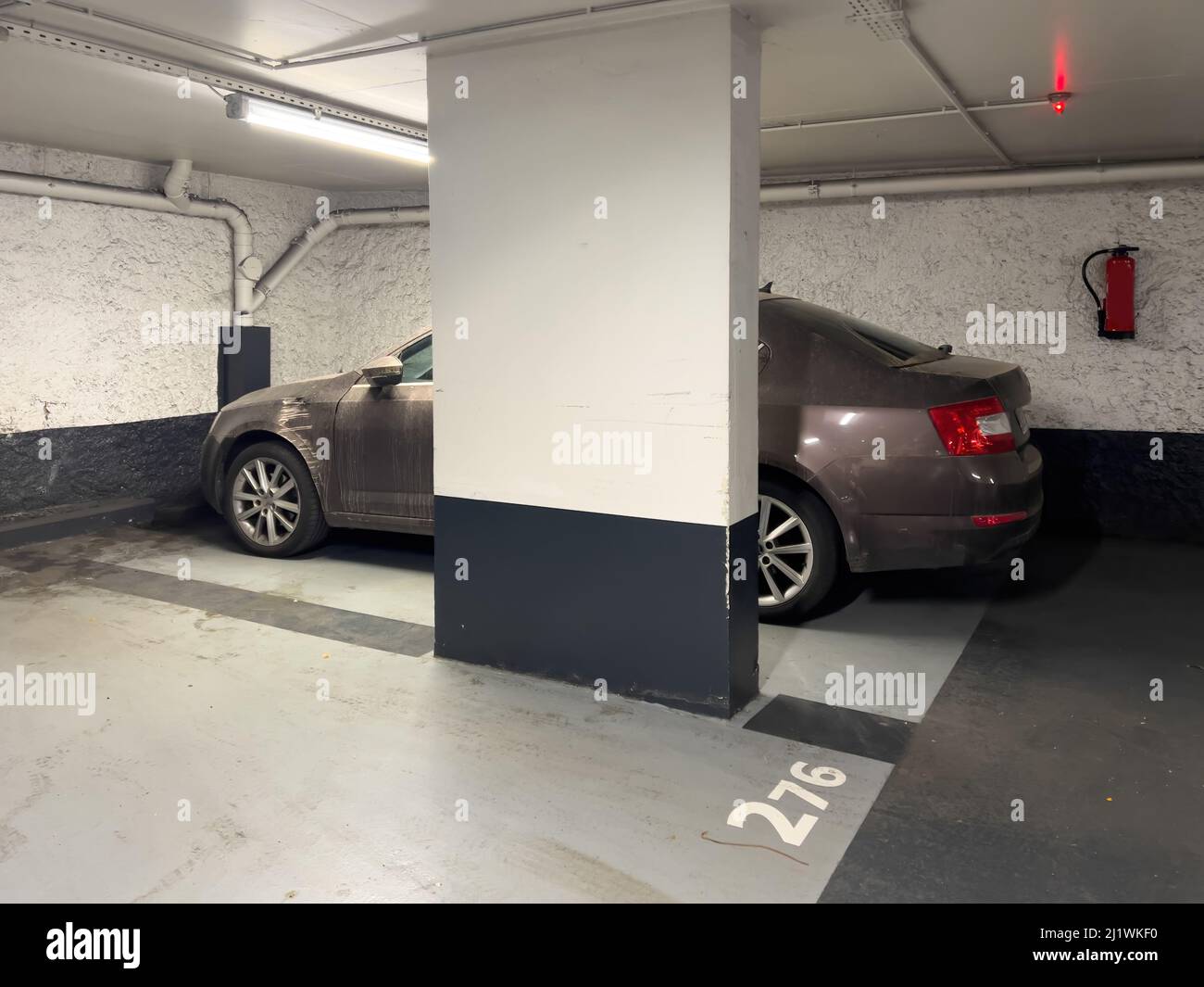 Car parked in underground parking with fire extinguisher on the wall