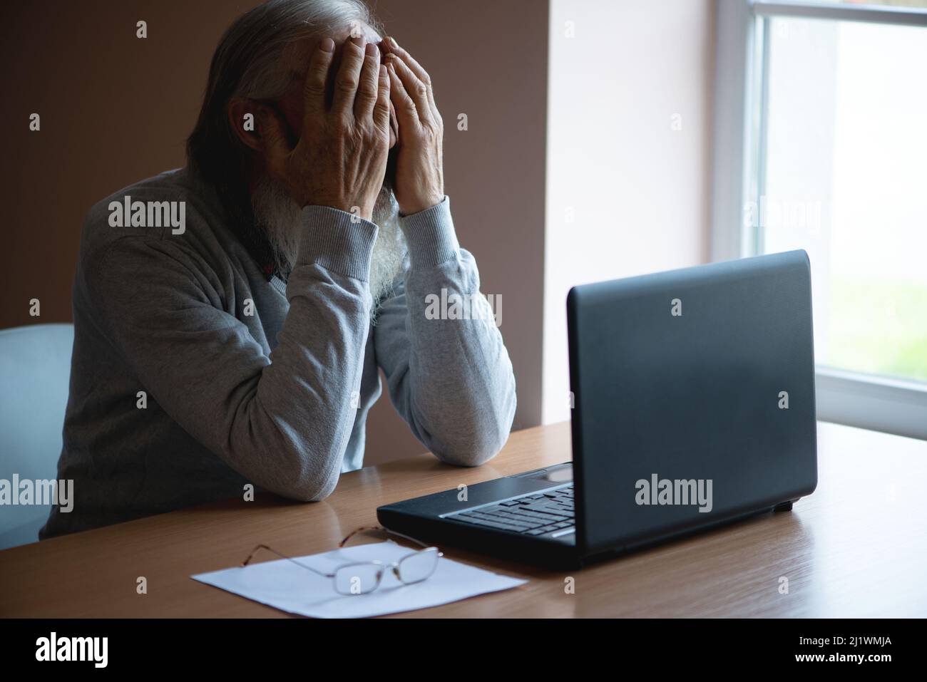 A tired, broken, resigned, preoccupied elderly man sits in front of a ...