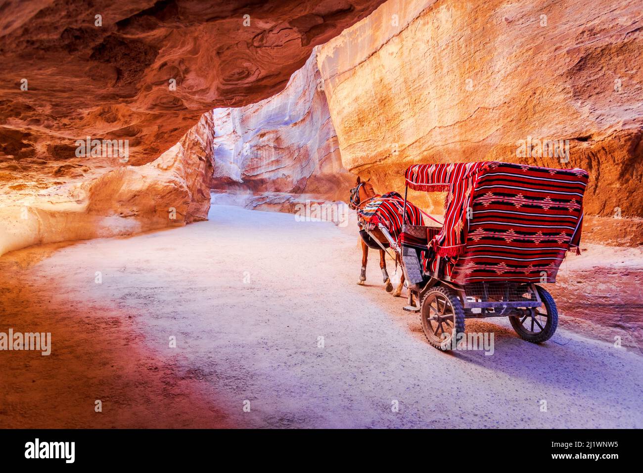 Petra, Jordan. A horse cart carrying tourists on dusty road in Petra, Wadi Rum. One of the worlds greatest archeological sites. Stock Photo