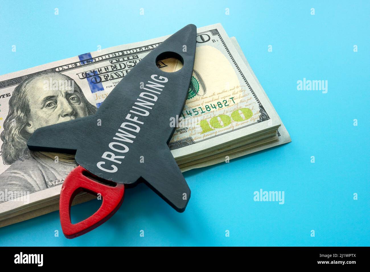 Rocket with the inscription crowdfunding and a bundle of money. Stock Photo