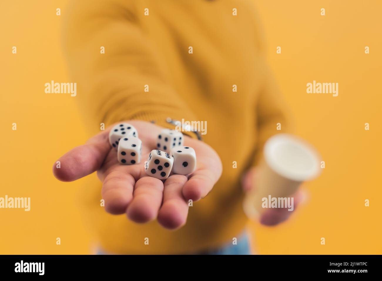 Five dice lying on a hand of a caucasian person. Studio shot over yellow background. High quality photo Stock Photo