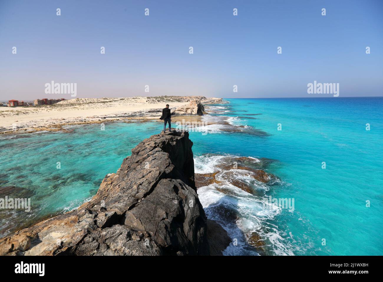 Marsa Matrouh, Egypt. 27th Mar, 2022. A tourist enjoys the scenery of Cleopatra Beach at the north coast city of Marsa Matrouh, Egypt, March 27, 2022. Marsa Matrouh, a resort city on the coast of the Mediterranean Sea, is famous for its soft white sandy beaches and transparent sapphire-color sea water. Credit: Sui Xiankai/Xinhua/Alamy Live News Stock Photo