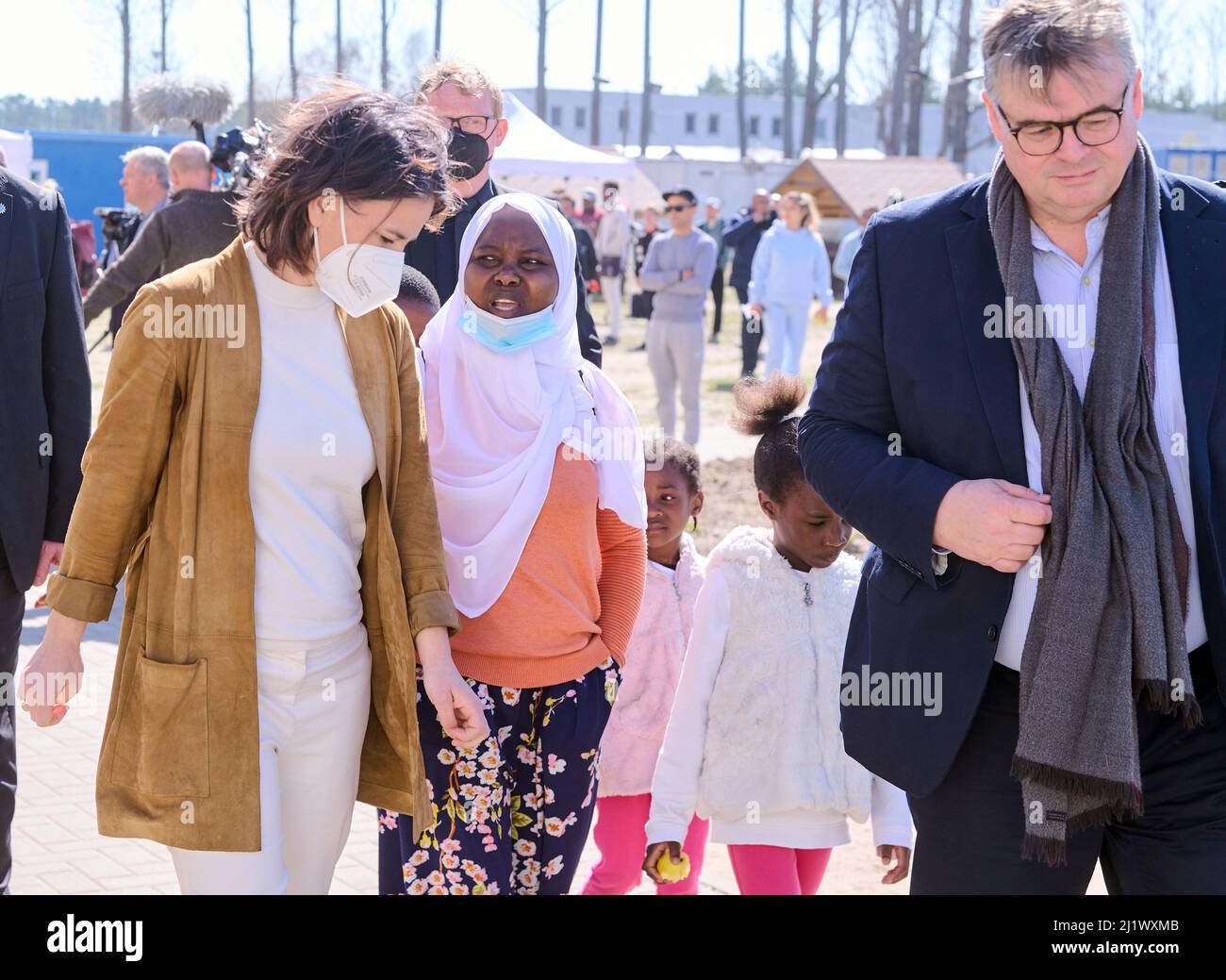 28 March 2022, Brandenburg, Eisenhüttenstadt: Annalena Baerbock (Bündnis 90/ Die Grünen), Federal Minister for Foreign Affairs, talks to a refugee woman who lives with her children in the Central Initial Reception Facility for Asylum Seekers. Olaf Jansen, head of the Central Immigration Office (ZABH) in Eisenhüttenstadt walks beside them. Photo: Annette Riedl/dpa Stock Photo