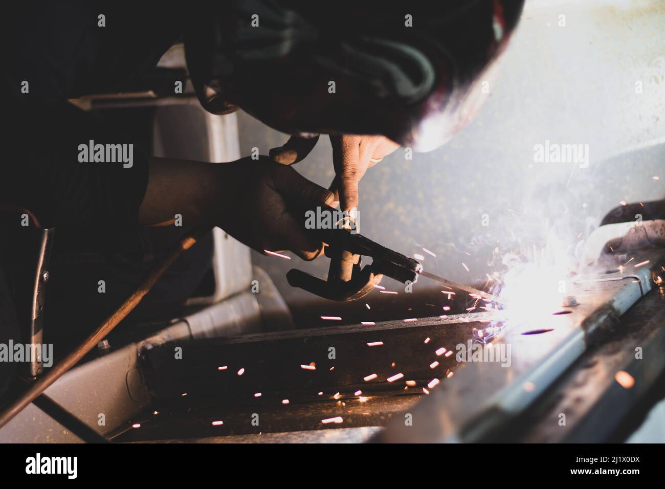 A closeup shot of a  metal fabricator making an automotive welding with flames in a car factory Stock Photo