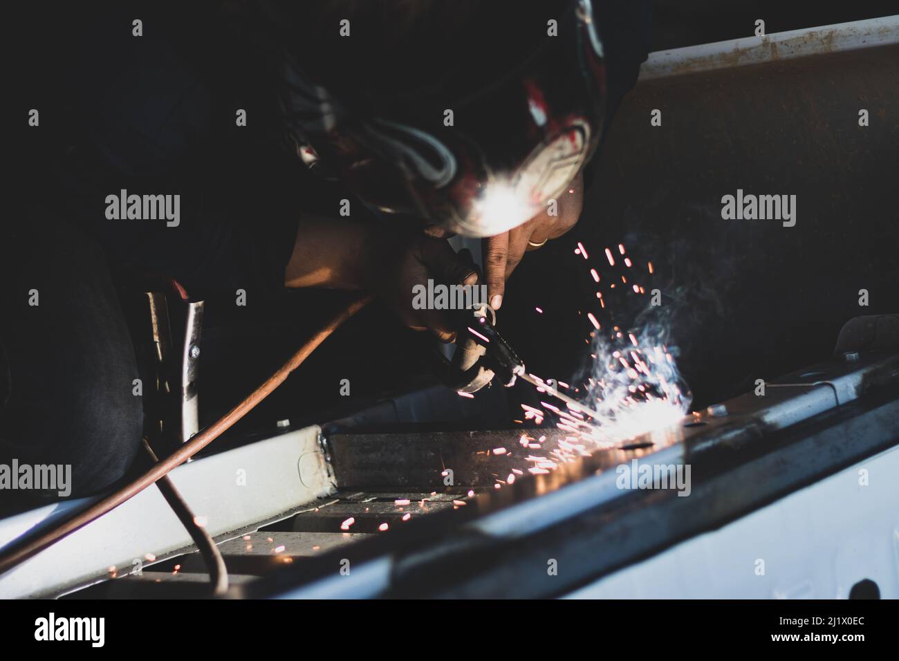 A closeup shot of a  metal fabricator making automotive welding with flames in a car factory Stock Photo
