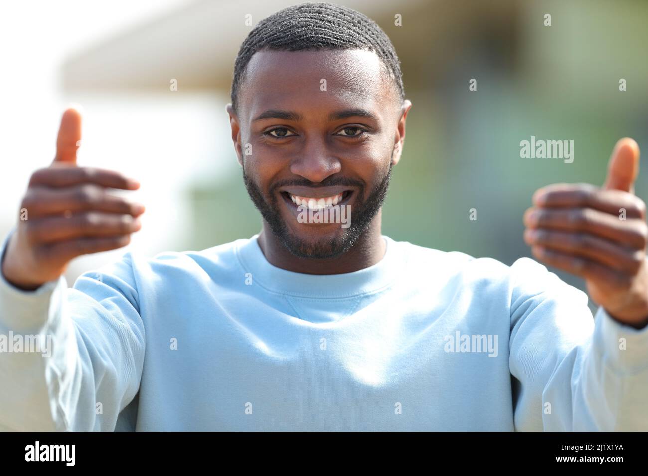 Front view portrait of a happy man with black skin saying come in the street Stock Photo