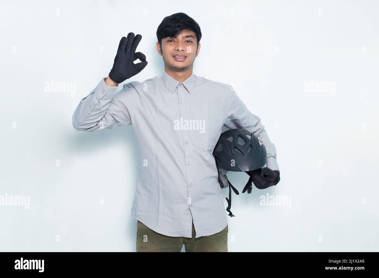 handsome asian man with a motorcycle helmet showing a thumbs up ok gesture on white background Stock Photo