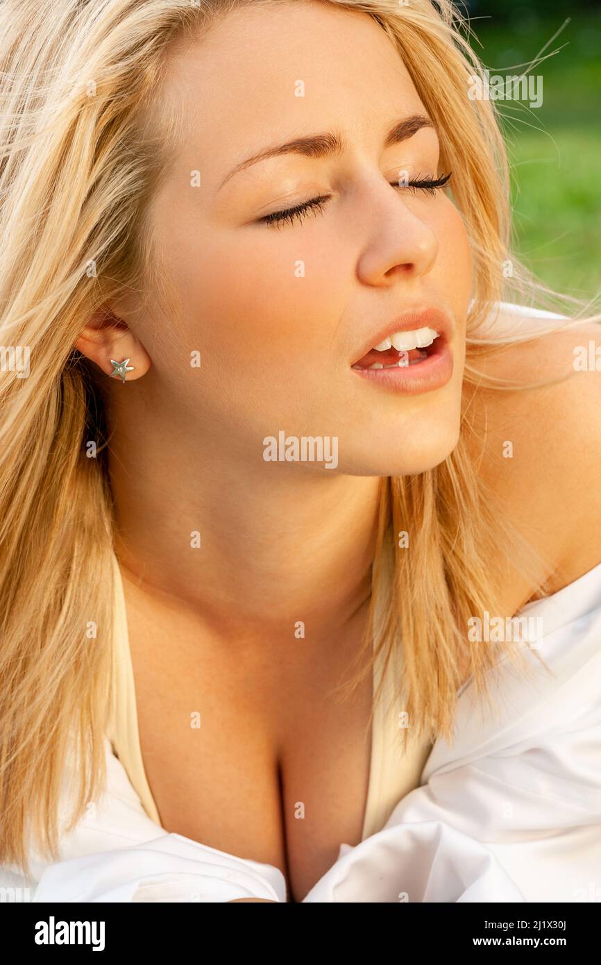 Outdoor portrait of happy, beautiful female young woman with blonde hair outside eyes closed in sunshine Stock Photo
