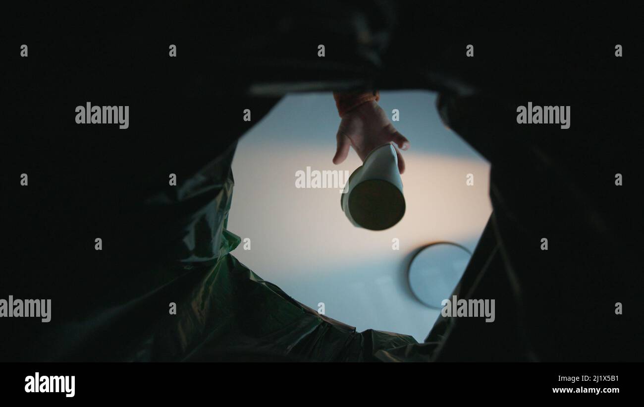 Hand putting paper cup in recycling bin. Bottom view from the trash bin ...