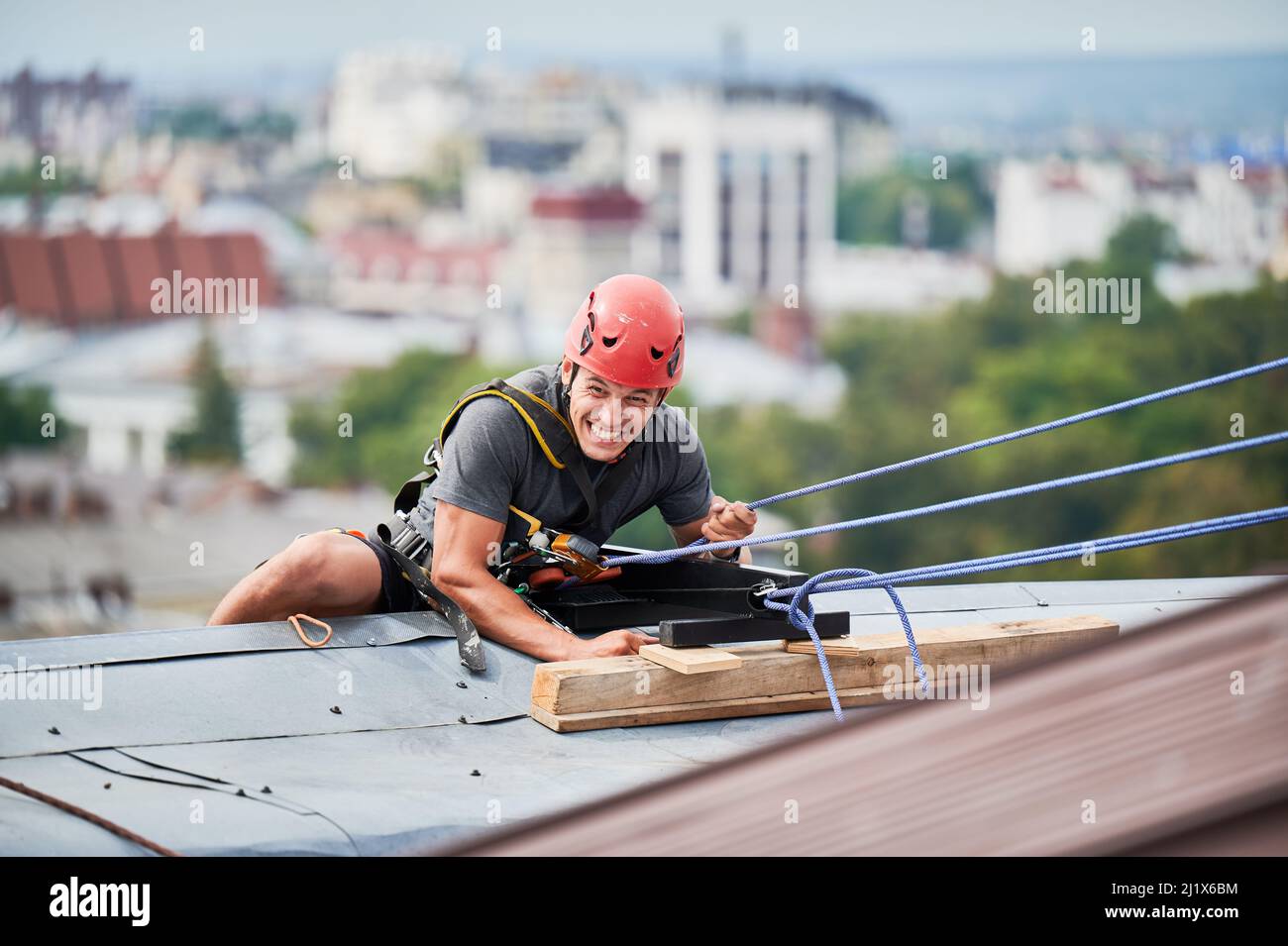 Industrial mountaineering worker in protective helmet using safety climbing rope while climbing