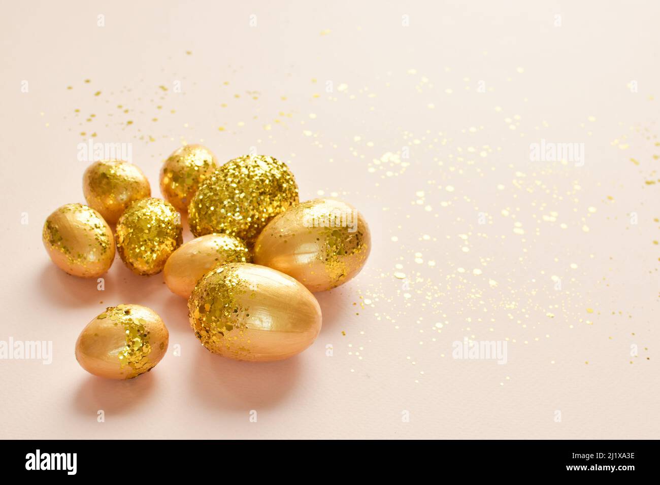 Easter eggs with gold sequins on a beige background. Stock Photo
