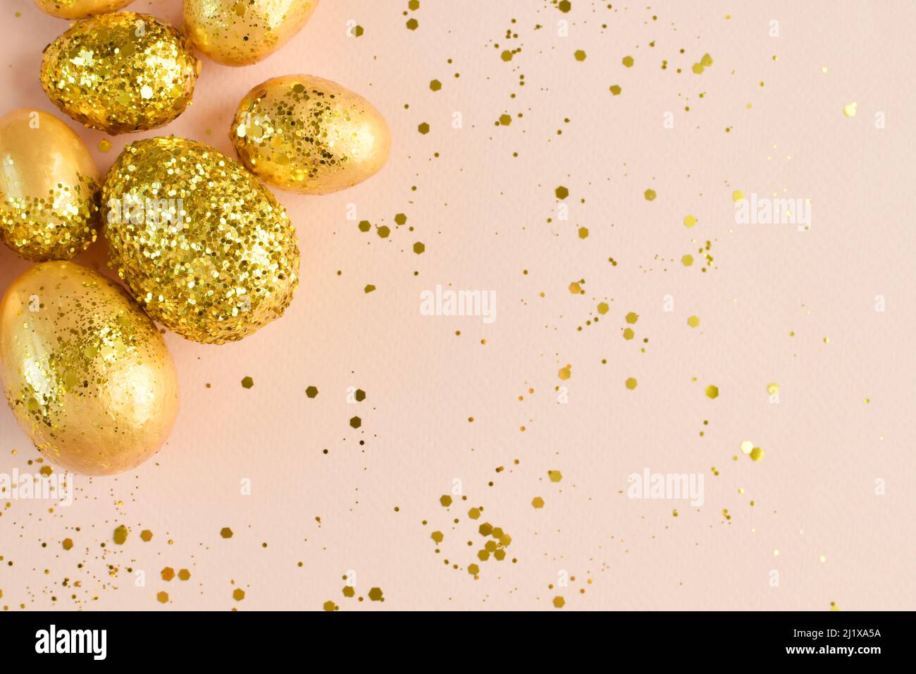 Easter eggs with gold sequins on a beige background. Stock Photo