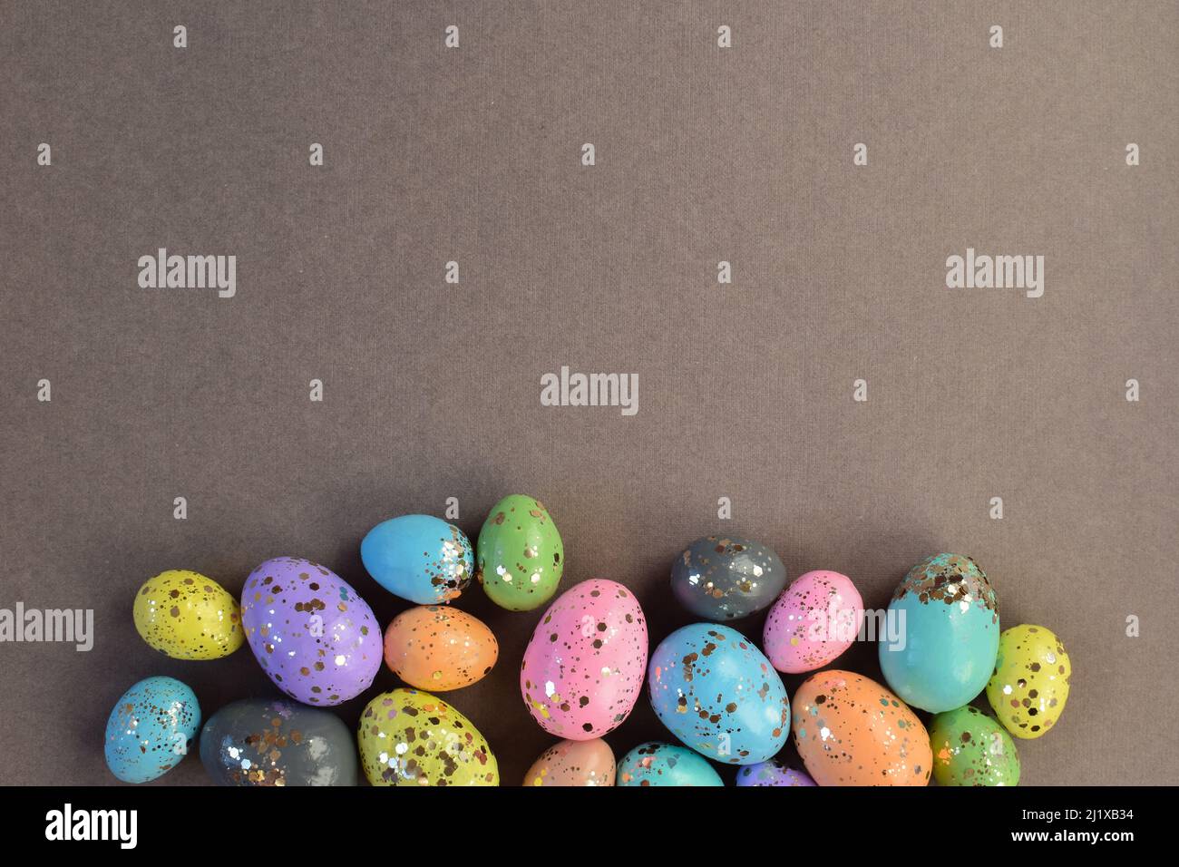 Easter card with bed-colored eggs and sequins on a gray background. Stock Photo