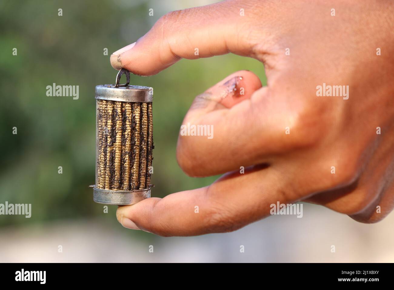 Oil filter with lots of metal pieces struck on its surfaces held in the hand Stock Photo