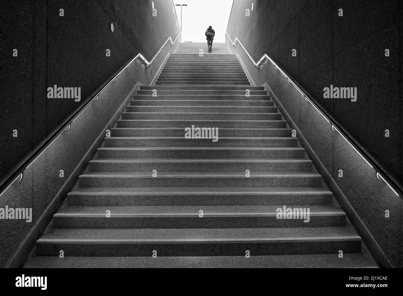 Man walking up dark stairs Stock Photo