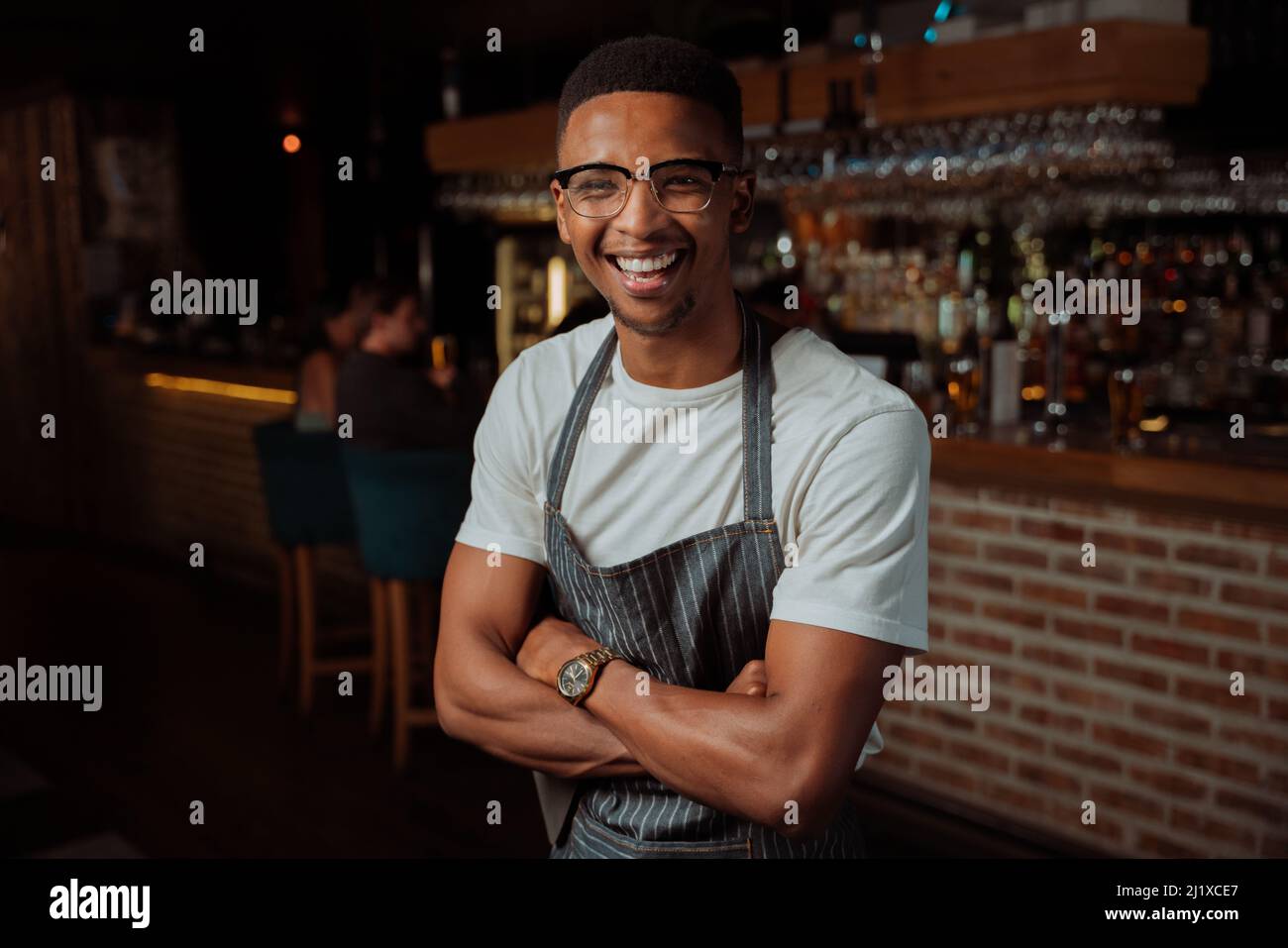 Portrait of Male waiter laughing while at work with apron Stock Photo