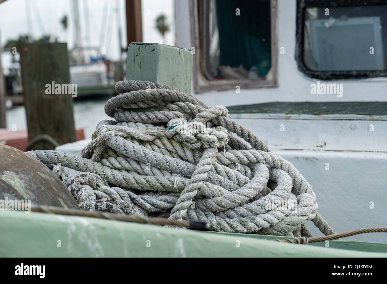 Rope piled up on deck of an old fishing boat in marina, in close up ...