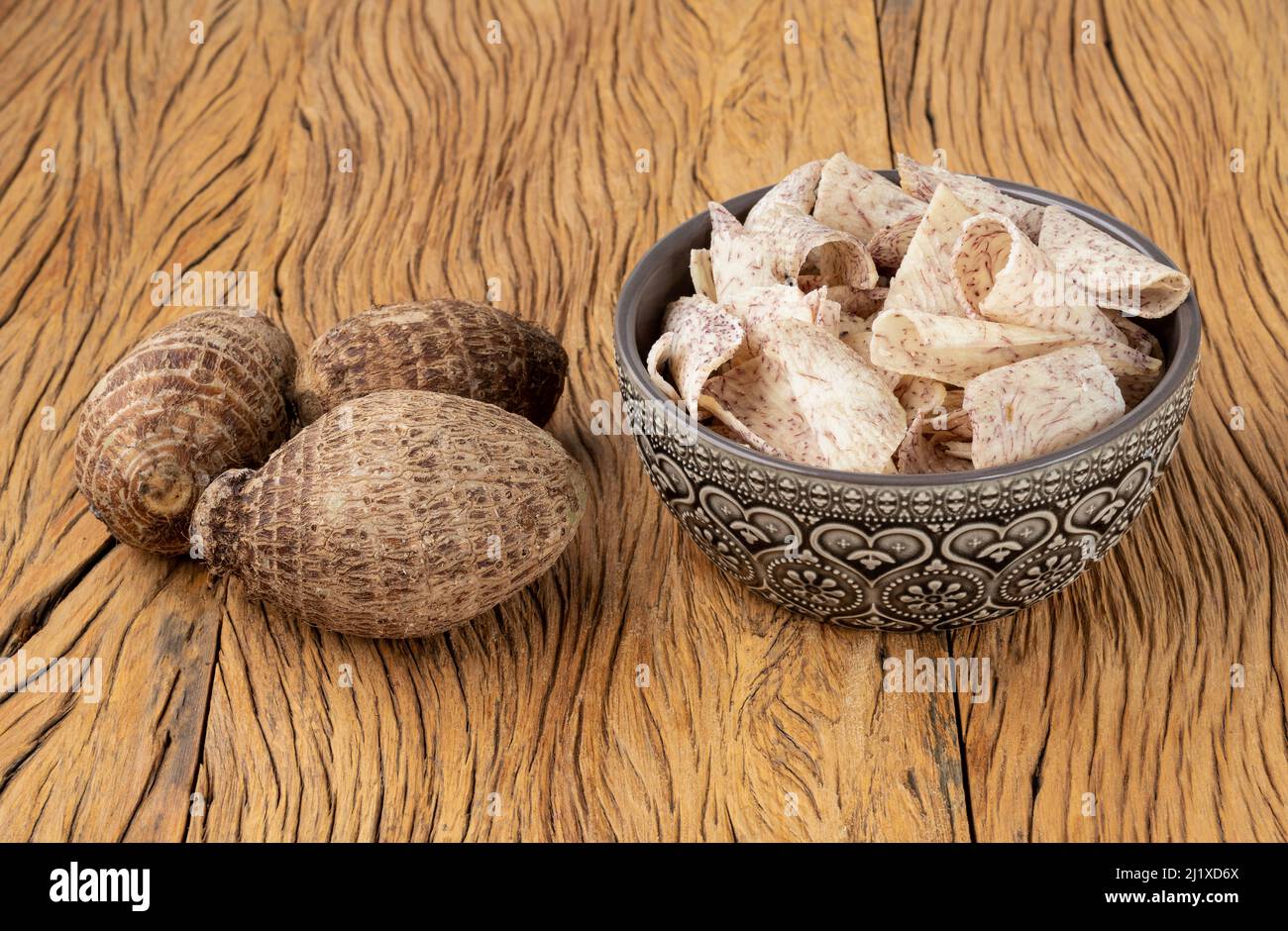 Yam or taro chips in a bowl with raw vegetable over wooden table. Stock Photo
