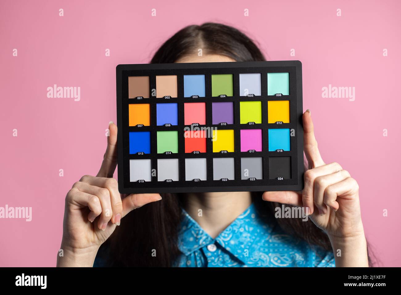 Palette or colorchecker calibration in the hands of a girl. The model holds a color card in its hands for correct color transfer during further color correction Stock Photo
