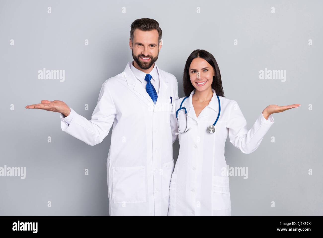 Photo of pretty happy two doctors wear white coats comparing arms empty