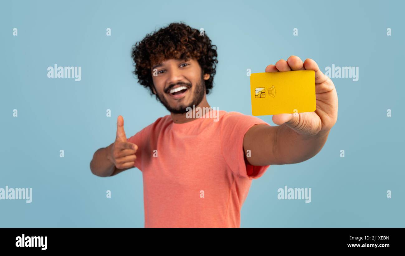 Cheerful young indian man showing credit card and thumb up Stock Photo ...