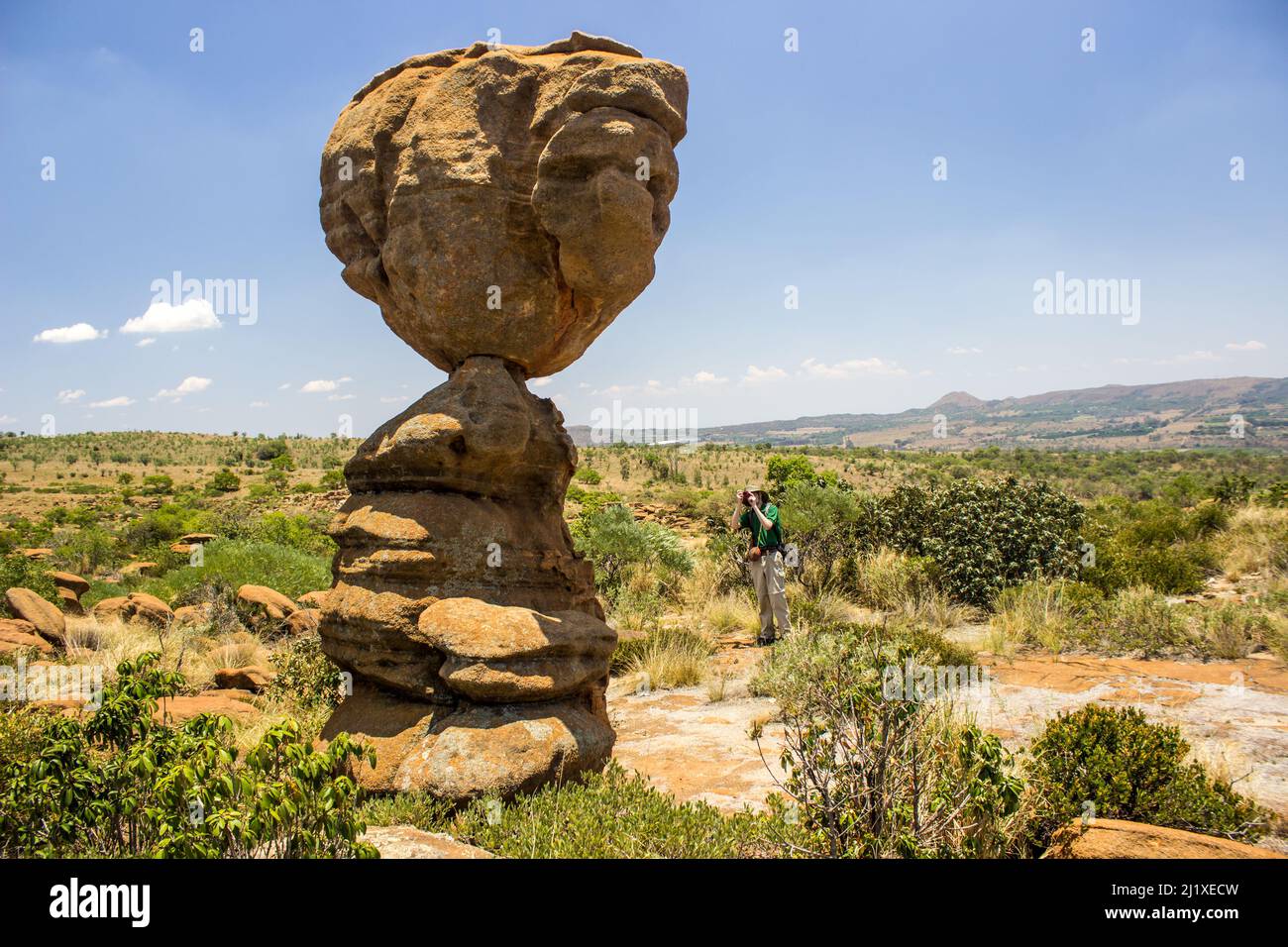 A photograph taking a photo of a tall balancing rock like rock pillar on a sunny day in the Magaliesberg Mountains, South Africa Stock Photo