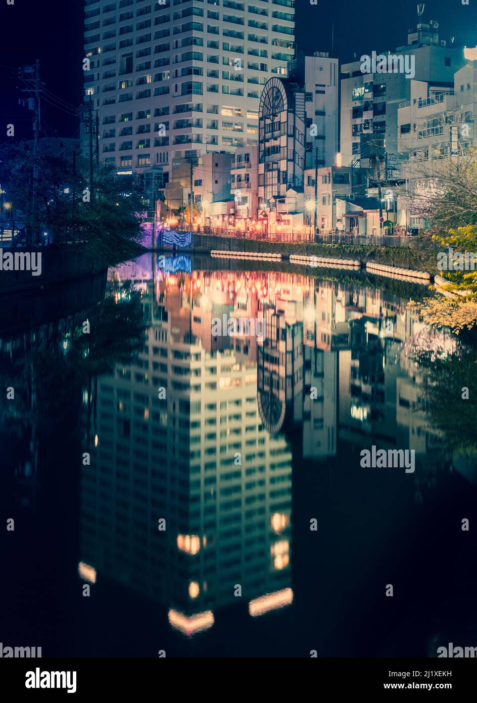 Shot of the Ooka River (大岡川) as it winds along the Hinode Sakura Michi street (日の出さくら道) near Hinodecho Station featuring reflections of a high-rise ap Stock Photo