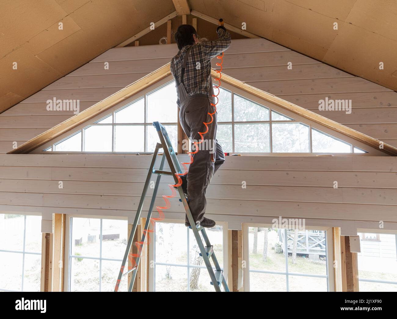 Construction worker thermally insulating eco wooden frame house Stock Photo