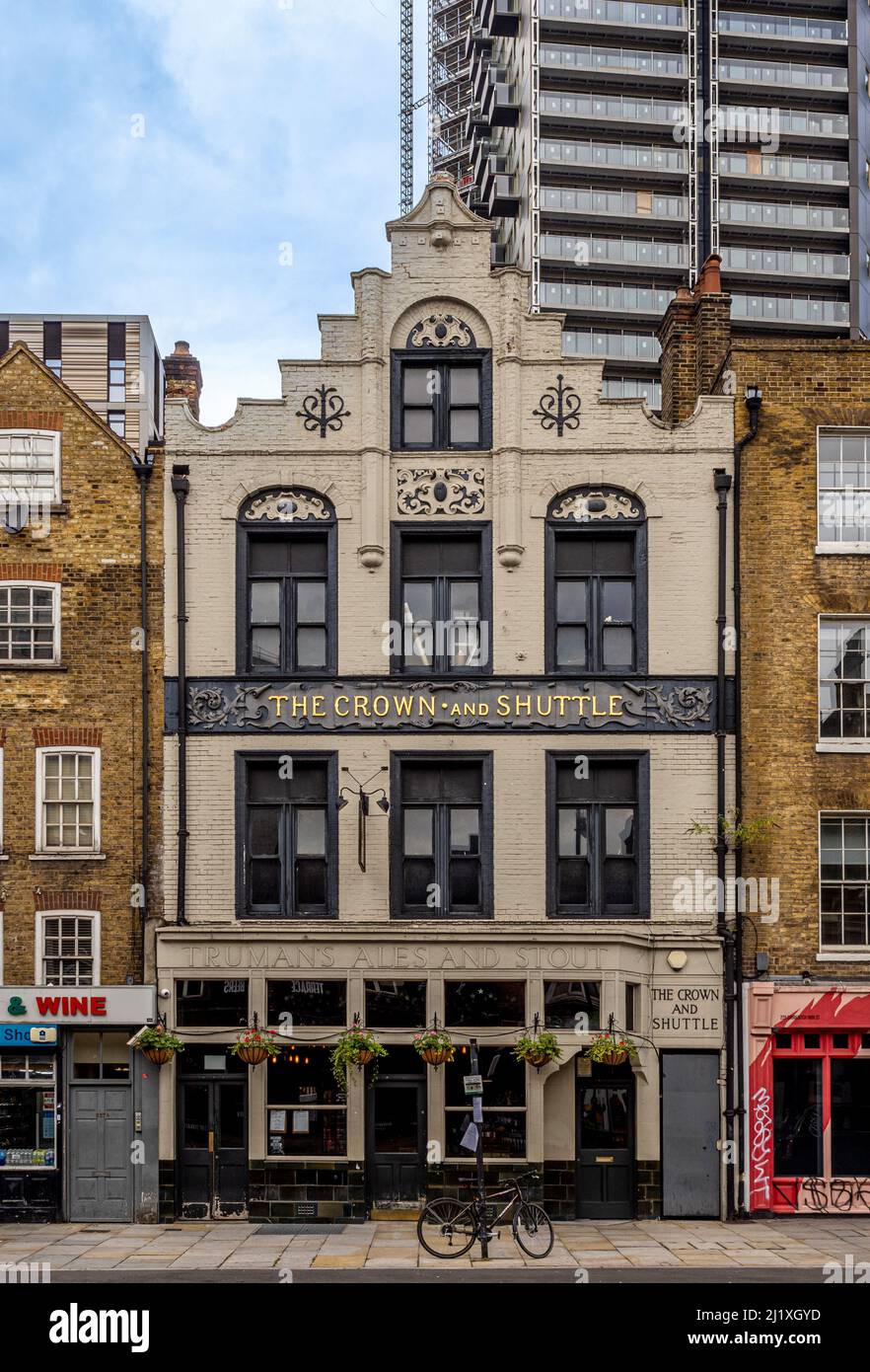 White exterior façade of The Crown and Shuttle public house on Shoreditch High Street with contemporary high-rise building behind. London. Stock Photo