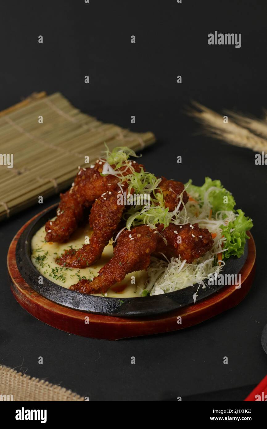 A vertical shot of fried Japanese chicken wings in a sauce served in