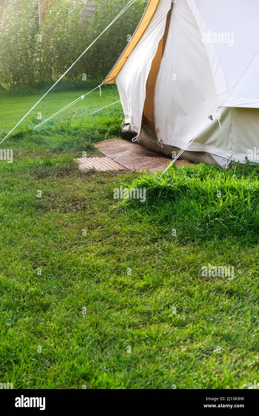 An old style canvas bell tent at a camp site in a lush green field set up for posh camping also known as glamping. Stock Photo