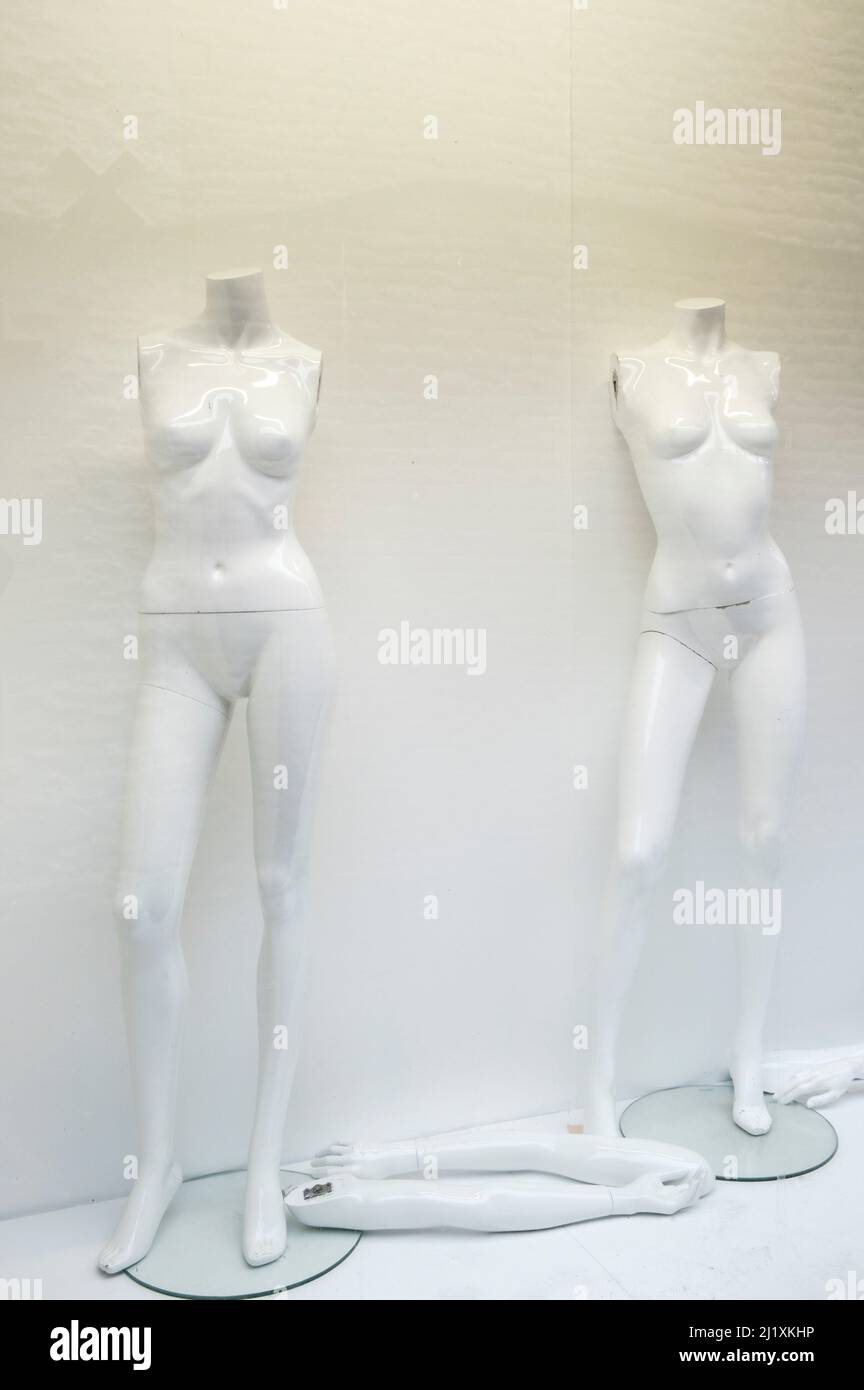Armless female mannequins in a shop window that has closed down, with no clothes on the dummies are naked. Stock Photo