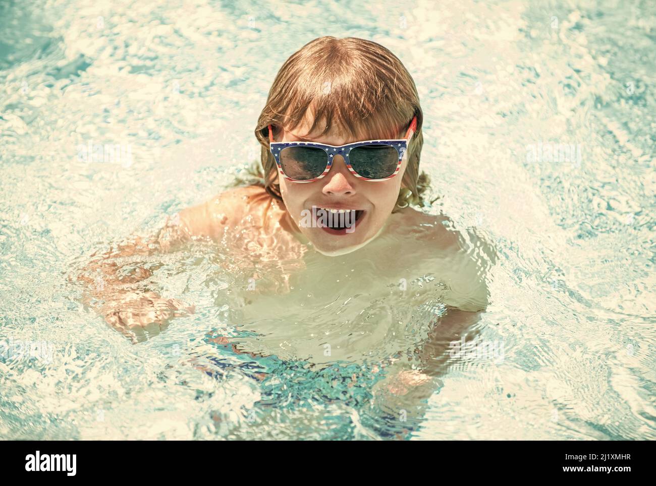 happy child boy in glasses swimming in pool, summer vacation Stock